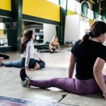 Women engaging in a group stretching session in an indoor gym.
